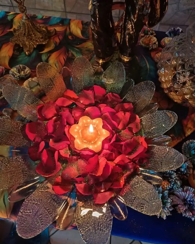 Pétalas de rosas vermelhas em volta de uma vela acesa em forma de flor